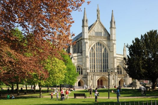 Winchester Cathedral and people view on a summers day through the trees